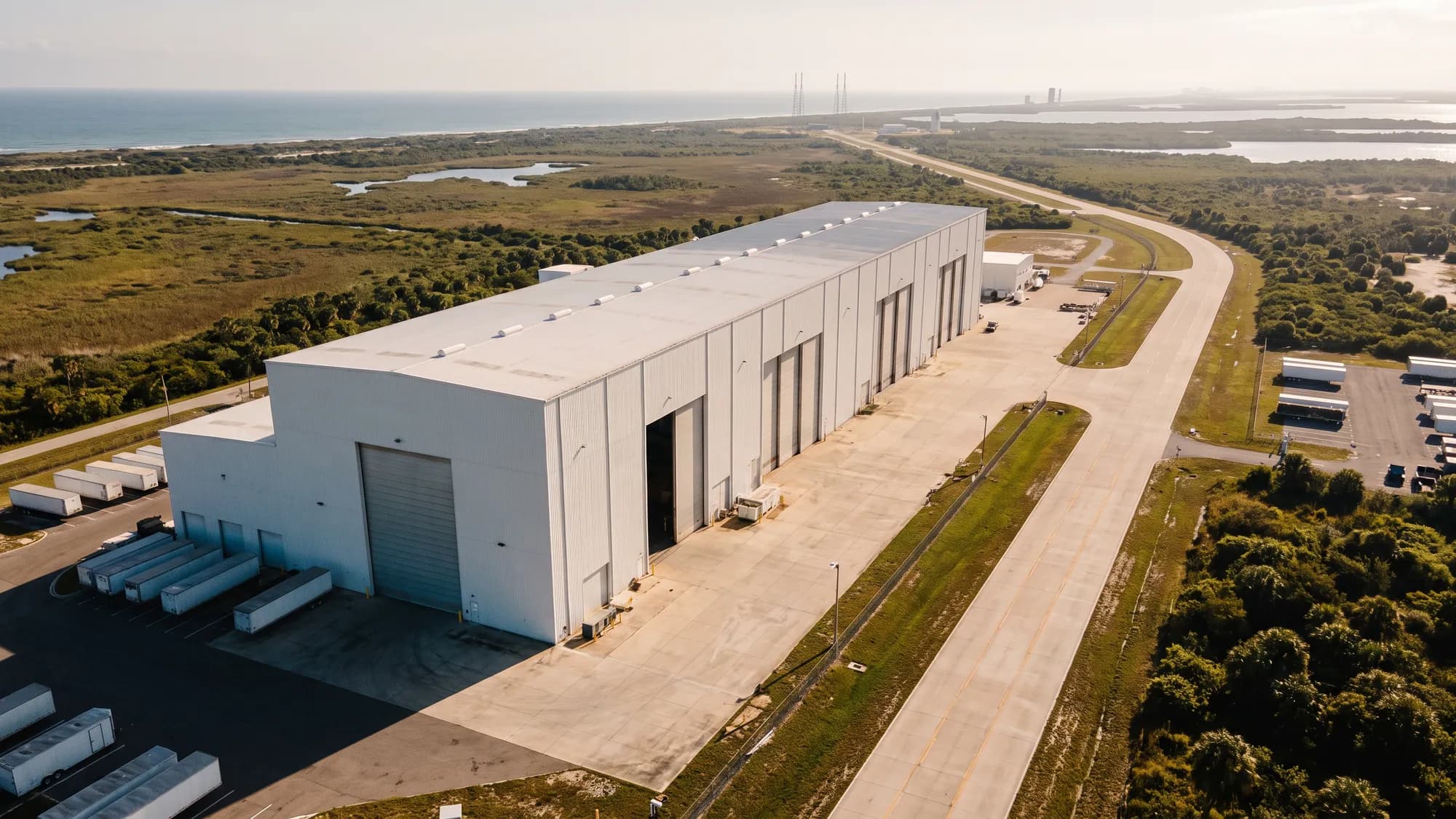 A large rocket manufacturing building near the Florida coast with launch pads in the distance