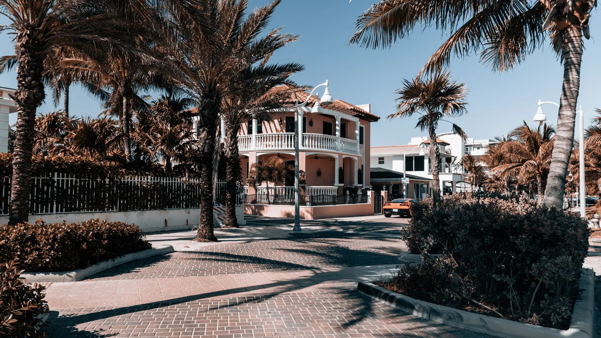 A two-story house behind palms on a street in Hollywood, Florida
