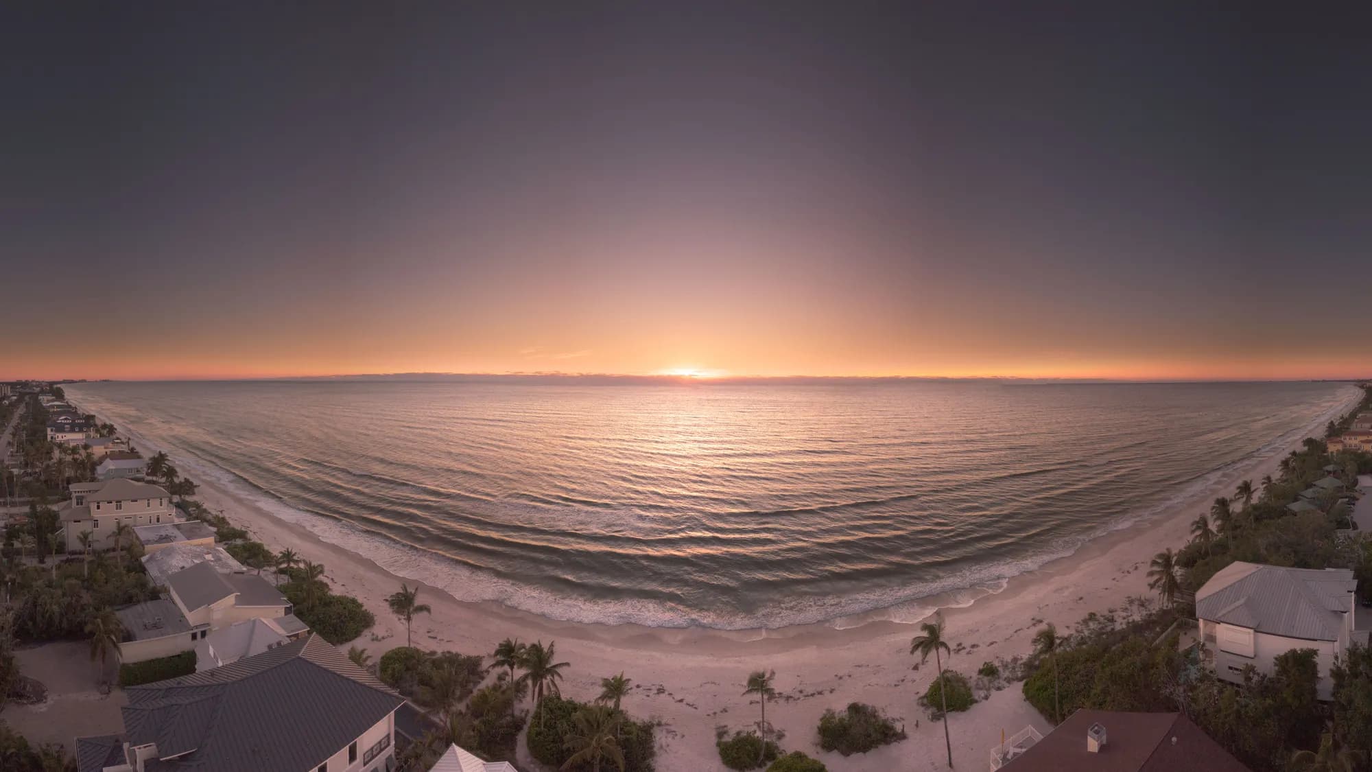 Houses lining the shore at sunset, seen from above